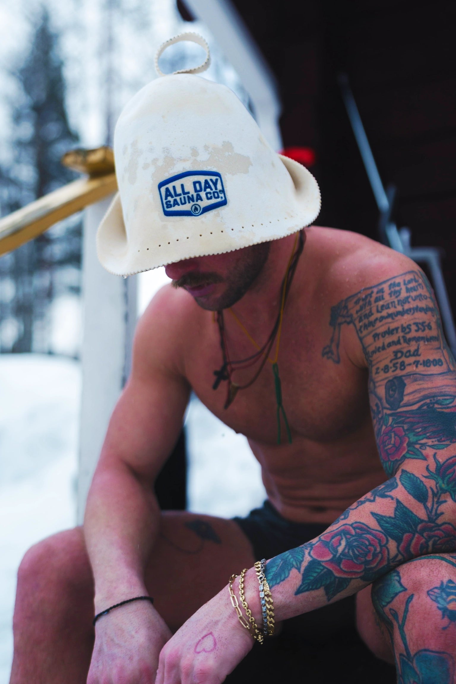 Person wearing All Day Sauna Co. wool sauna hat outside a wood-fired sauna — cozy and heat-insulating headwear