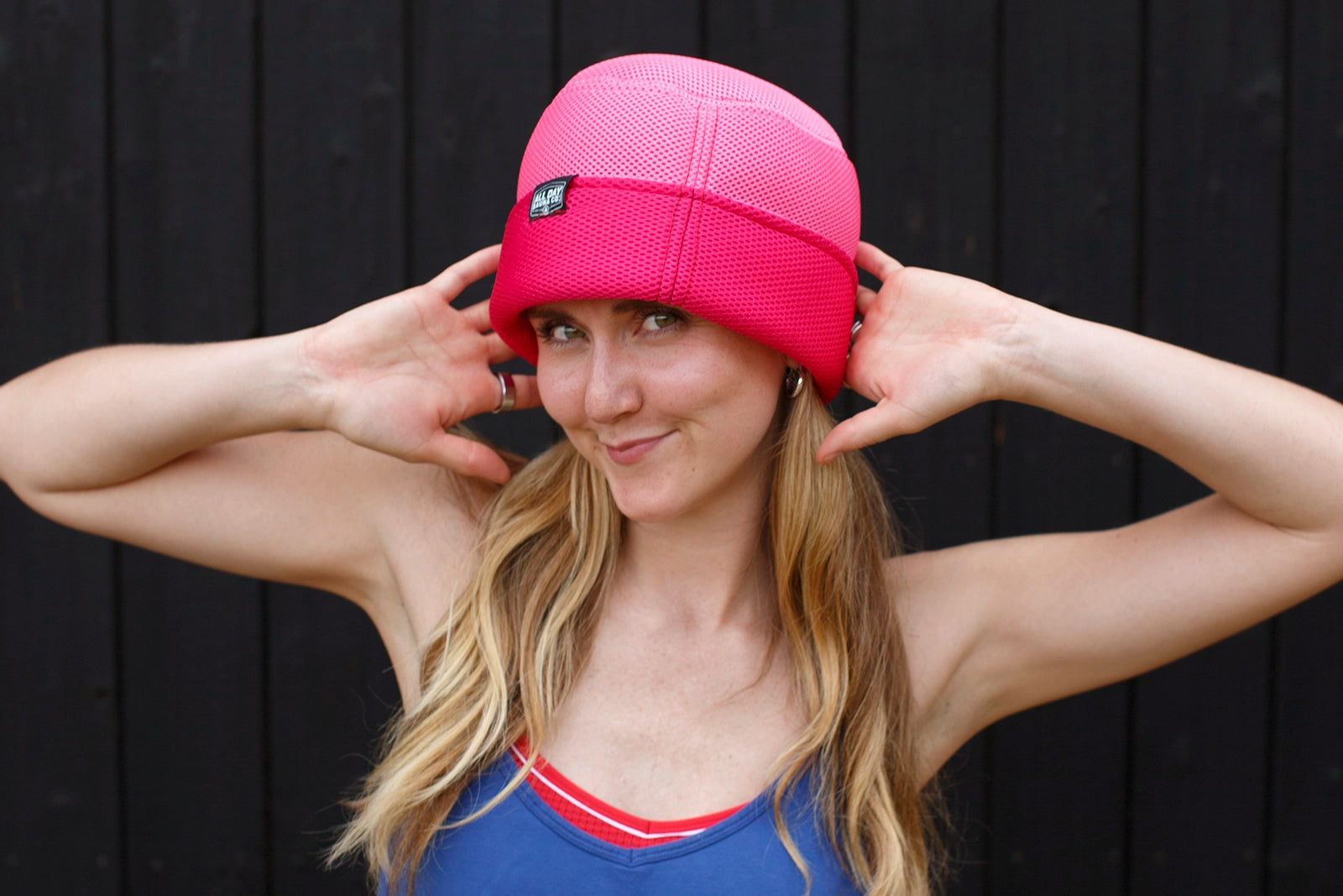 Woman wearing Pink All Day Sauna Co. mesh sauna hat during outdoor sauna session — lightweight and breathable headwear for heat protection.