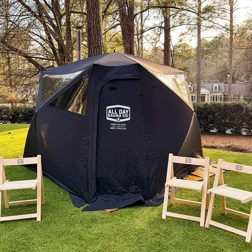 Outdoor sauna tent showing fire‑resistant material, natural lighting window, reinforced tie‑downs, and chairs.