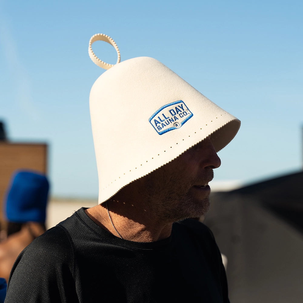 Sauna enthusiast wearing wool sauna hat from All Day Sauna Co. while outside backyard sauna.